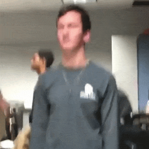 An animated GIF of guy who strangely resembles Charlie Kirk (RIP Bozo) standing still with a blank expression as various phone cases get thrown at his face, followed by him getting hit by a large cardboard box.